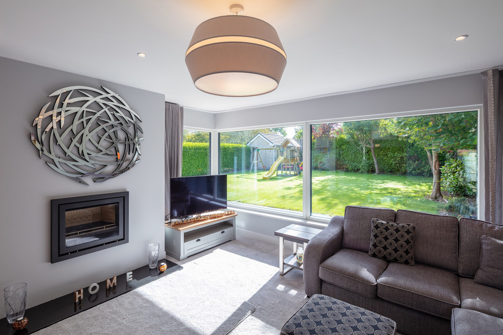 Photo of a medium sized modern open plan living room in Other with grey walls, carpet, a wood burning stove, a metal fireplace surround, a freestanding tv and grey floors.