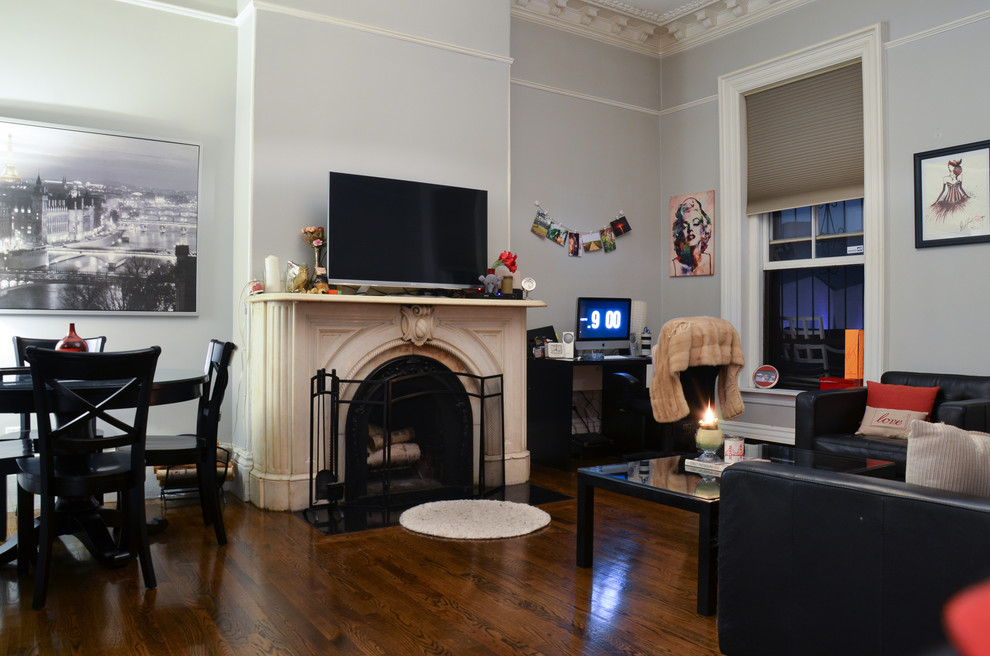 Kleines, Abgetrenntes Modernes Wohnzimmer mit grauer Wandfarbe, dunklem Holzboden, Kamin, Kaminumrandung aus Stein und freistehendem TV in Boston