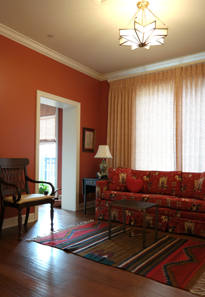 Immagine di un soggiorno eclettico di medie dimensioni e chiuso con sala formale, pareti arancioni, parquet scuro e pavimento marrone