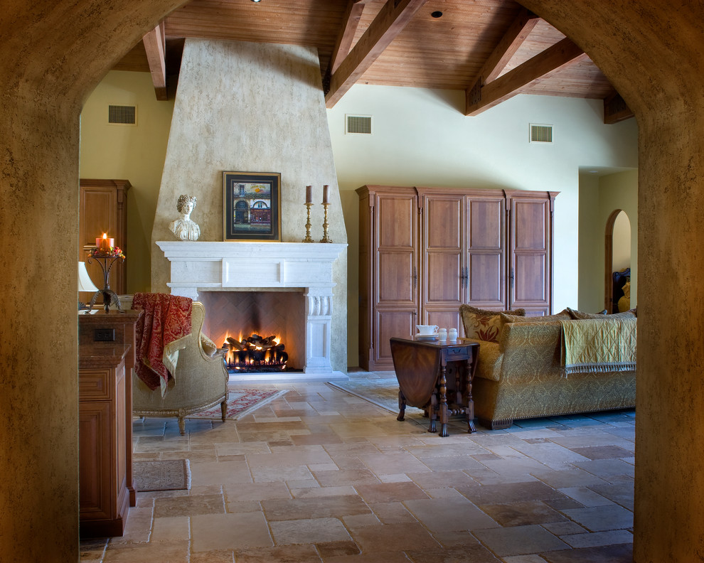 Пример оригинального дизайна: огромная гостиная комната в средиземноморском стиле с бежевыми стенами, полом из травертина, стандартным камином, фасадом камина из камня и скрытым телевизором