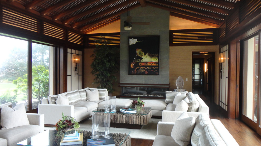 マイアミにあるラグジュアリーな広いアジアンスタイルのおしゃれなリビング (ベージュの壁、無垢フローリング、横長型暖炉、タイルの暖炉まわり、茶色い床) の写真
