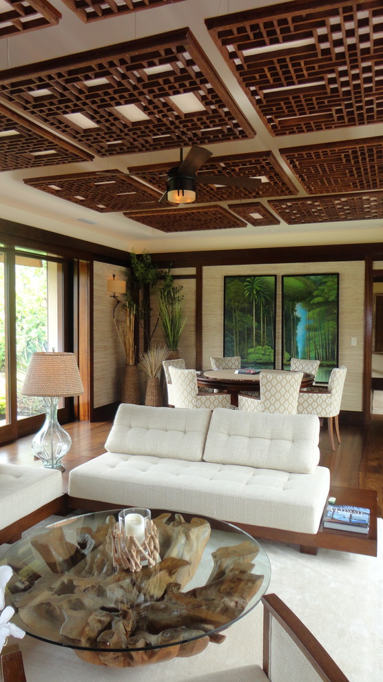 Immagine di un grande soggiorno tropicale chiuso con pareti beige, pavimento in legno massello medio, nessun camino, TV a parete e pavimento marrone