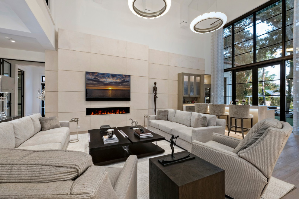 На фото: огромная гостиная комната в современном стиле с бежевыми стенами, ковровым покрытием и телевизором на стене с