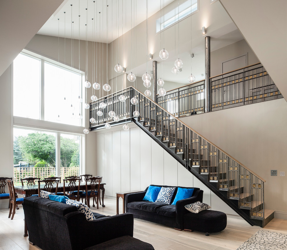 Réalisation d'un salon design ouvert avec un mur blanc, parquet clair et un escalier.