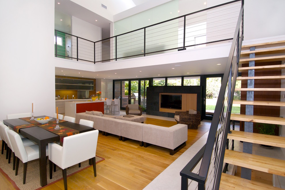 Пример оригинального дизайна: гостиная комната в стиле модернизм с белыми стенами, светлым паркетным полом, стандартным камином, фасадом камина из дерева и мультимедийным центром