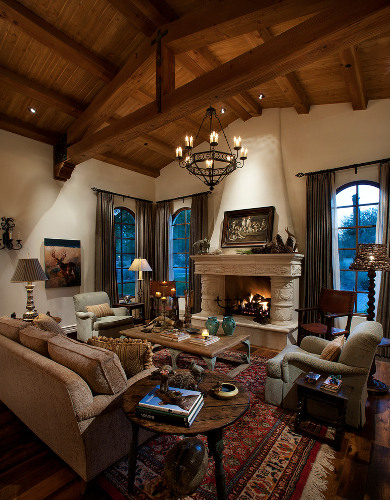 This is an example of a large mediterranean open plan living room in Phoenix with beige walls, dark hardwood flooring, a standard fireplace, a stone fireplace surround and no tv.