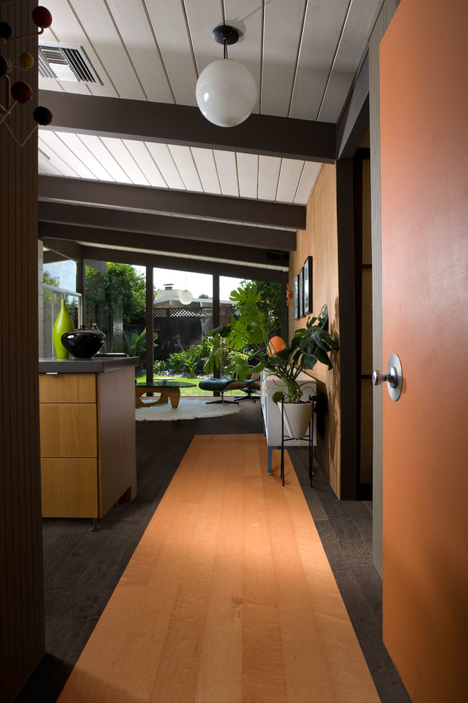 Exempel på ett mellanstort amerikanskt allrum med öppen planlösning, med en hemmabar, orange väggar och ljust trägolv