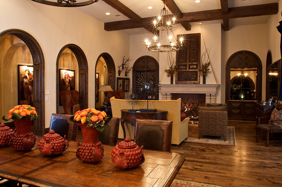 Offenes Mediterranes Wohnzimmer mit beiger Wandfarbe, braunem Holzboden, Kamin und Kaminumrandung aus Stein in Dallas