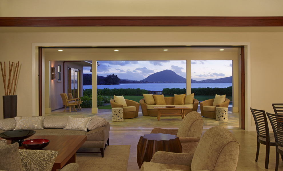 ハワイにあるラグジュアリーな広いトロピカルスタイルのおしゃれなLDK (白い壁、トラバーチンの床、壁掛け型テレビ) の写真