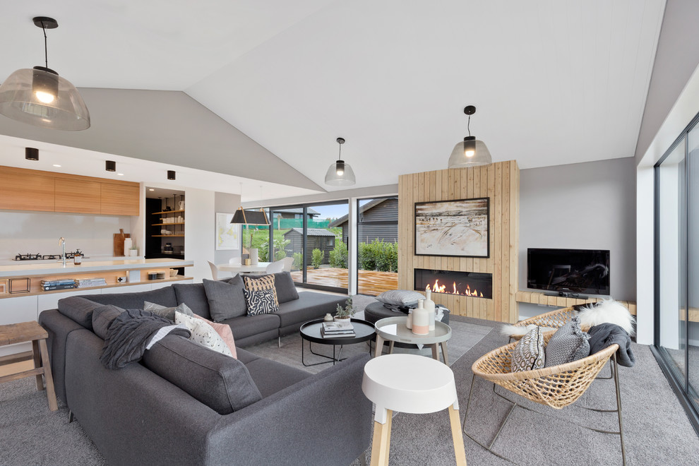 Großes, Repräsentatives, Offenes Modernes Wohnzimmer mit grauer Wandfarbe, Teppichboden, Hängekamin, Kaminumrandung aus Holz, freistehendem TV und grauem Boden in Wellington