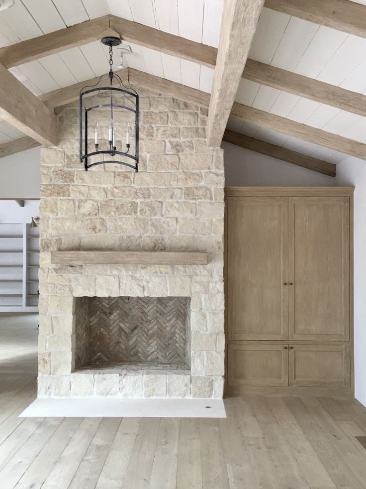 Modelo de salón abierto tradicional renovado de tamaño medio con paredes grises, suelo de madera clara, estufa de leña, marco de chimenea de piedra y suelo marrón