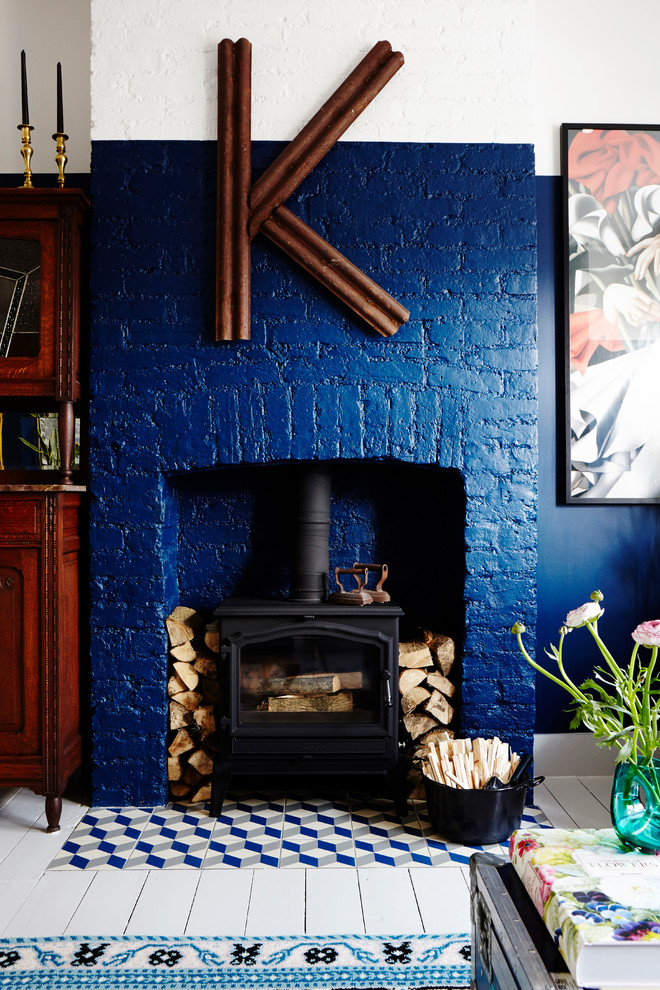 Cette image montre un grand salon craftsman ouvert avec une salle de réception, un mur bleu, parquet peint, un poêle à bois, un manteau de cheminée en brique, aucun téléviseur et un sol blanc.