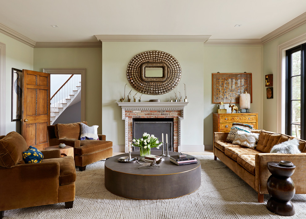 Klassisches Wohnzimmer mit grüner Wandfarbe, hellem Holzboden, Kamin, Kaminumrandung aus Backstein und beigem Boden in New York