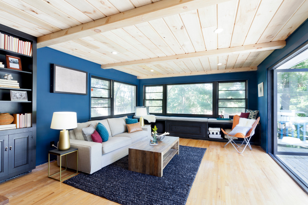 Photo of a contemporary living room in New York with blue walls and light hardwood flooring.
