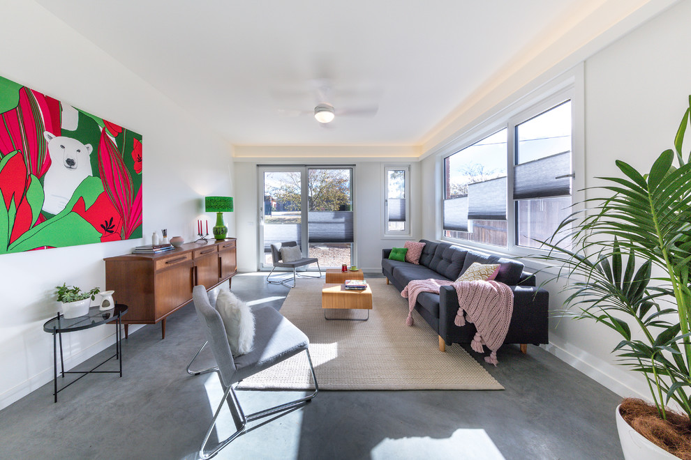 Small contemporary living room in Canberra - Queanbeyan with concrete flooring, a standard fireplace, a plastered fireplace surround and grey floors.