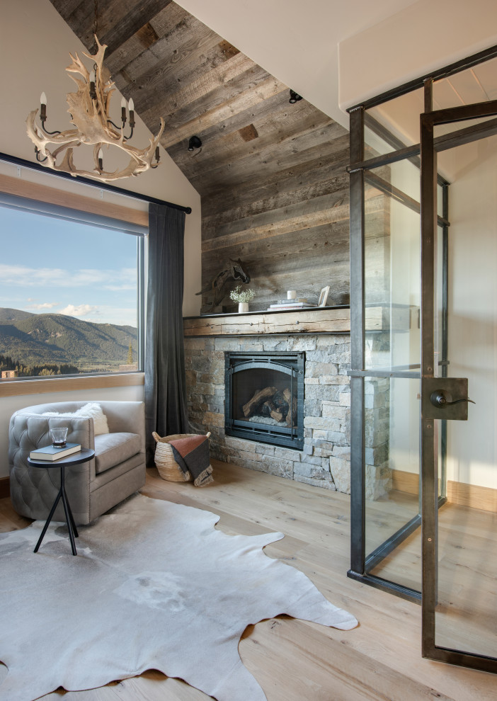 Example of a small mountain style loft-style light wood floor, brown floor and vaulted ceiling living room design in Other with white walls, a standard fireplace and a stone fireplace