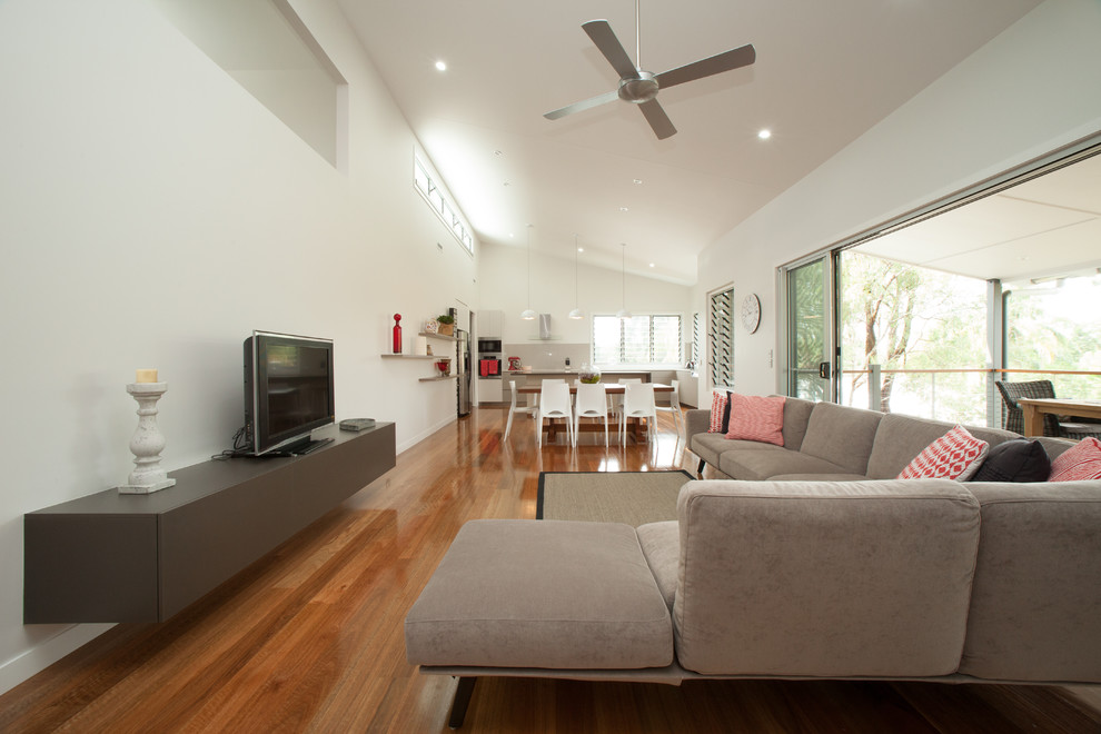 Idee per un grande soggiorno design aperto con pareti bianche, pavimento in legno massello medio e TV autoportante