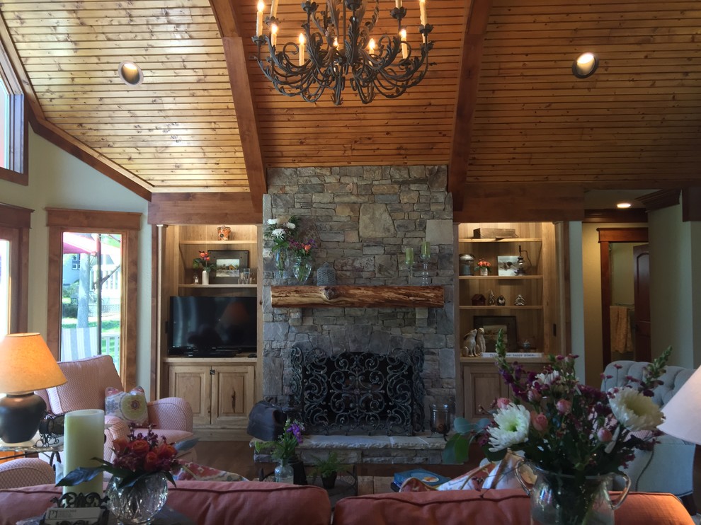 Cette photo montre un salon chic de taille moyenne et ouvert avec un bar de salon, un mur vert, un sol en bois brun, une cheminée standard, un manteau de cheminée en pierre et un téléviseur encastré.