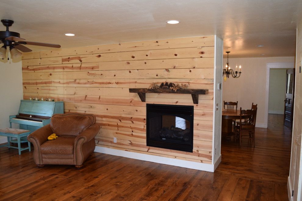 Exemple d'un salon nature de taille moyenne et fermé avec un mur blanc, un sol en bois brun, un téléviseur fixé au mur, un manteau de cheminée en bois et une cheminée double-face.