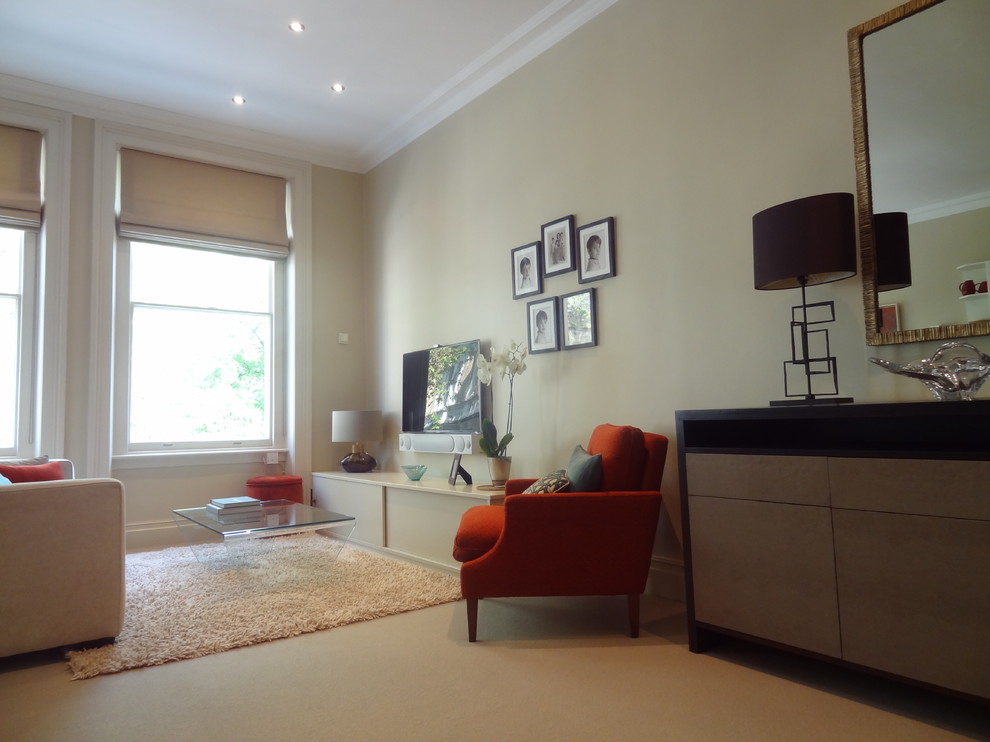 На фото: гостиная комната в стиле неоклассика (современная классика) с бежевыми стенами, ковровым покрытием и телевизором на стене