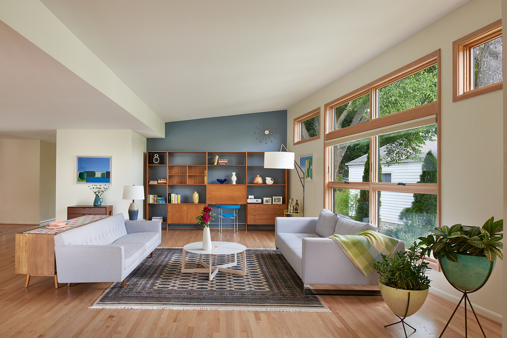 This is an example of a large retro formal open plan living room feature wall in DC Metro with light hardwood flooring, no tv, no fireplace, blue walls and beige floors.