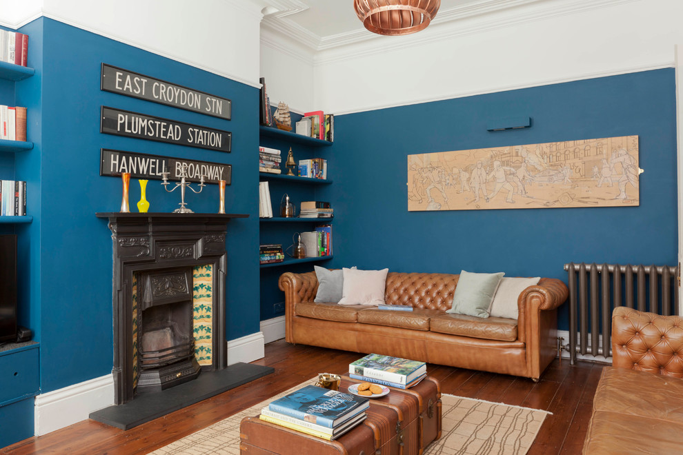 На фото: гостиная комната среднего размера в стиле фьюжн с синими стенами, полом из ламината, стандартным камином и коричневым полом с