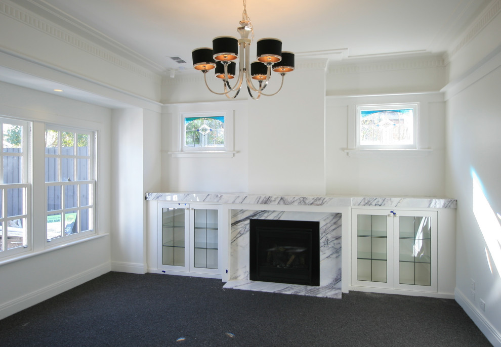 メルボルンにある小さなエクレクティックスタイルのおしゃれなリビング (白い壁、カーペット敷き、石材の暖炉まわり、テレビなし、グレーの床) の写真