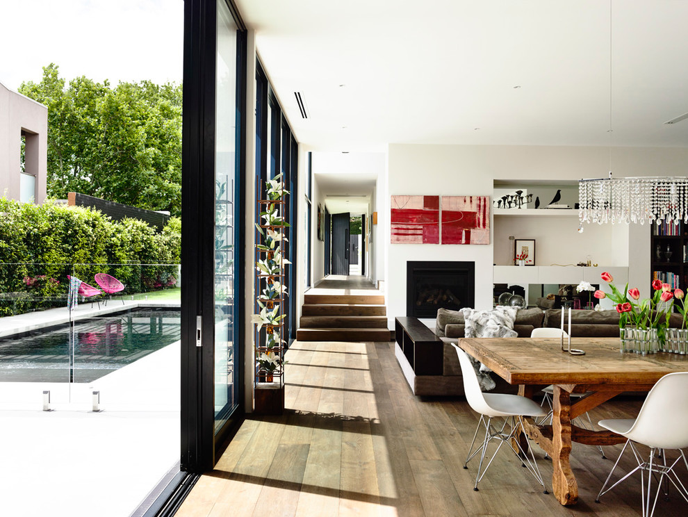Offenes Wohnzimmer mit weißer Wandfarbe, dunklem Holzboden, Kamin und verputzter Kaminumrandung in Melbourne