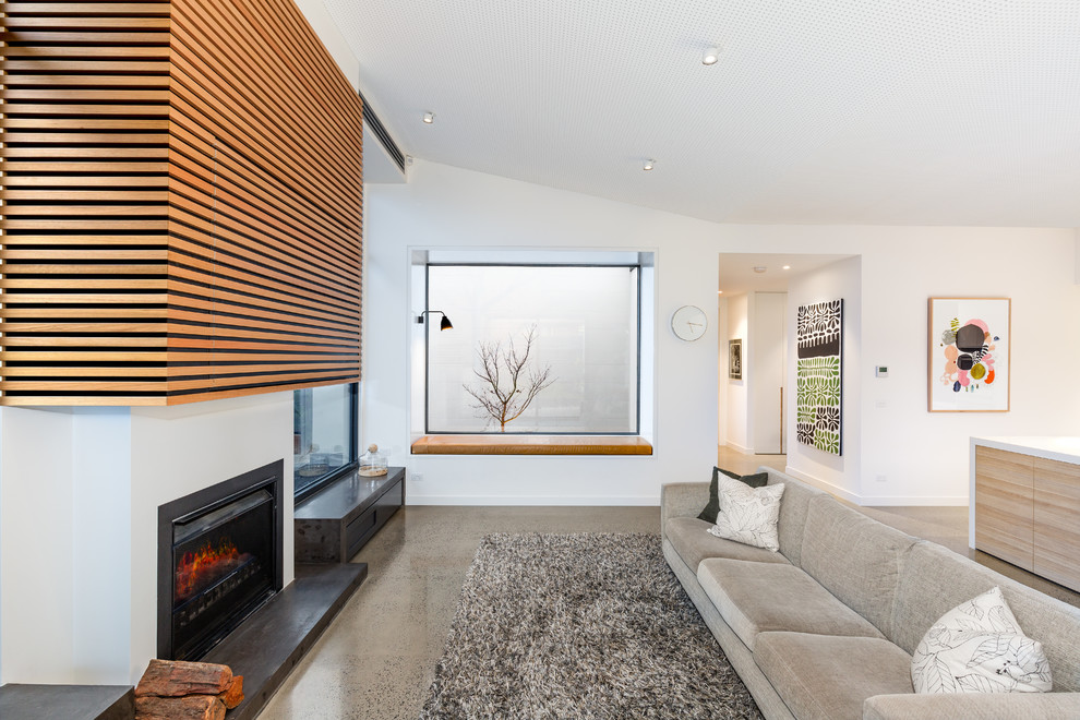 Offenes, Repräsentatives, Mittelgroßes Modernes Wohnzimmer mit weißer Wandfarbe, Betonboden, Kamin, Kaminumrandung aus Metall und beigem Boden in Melbourne