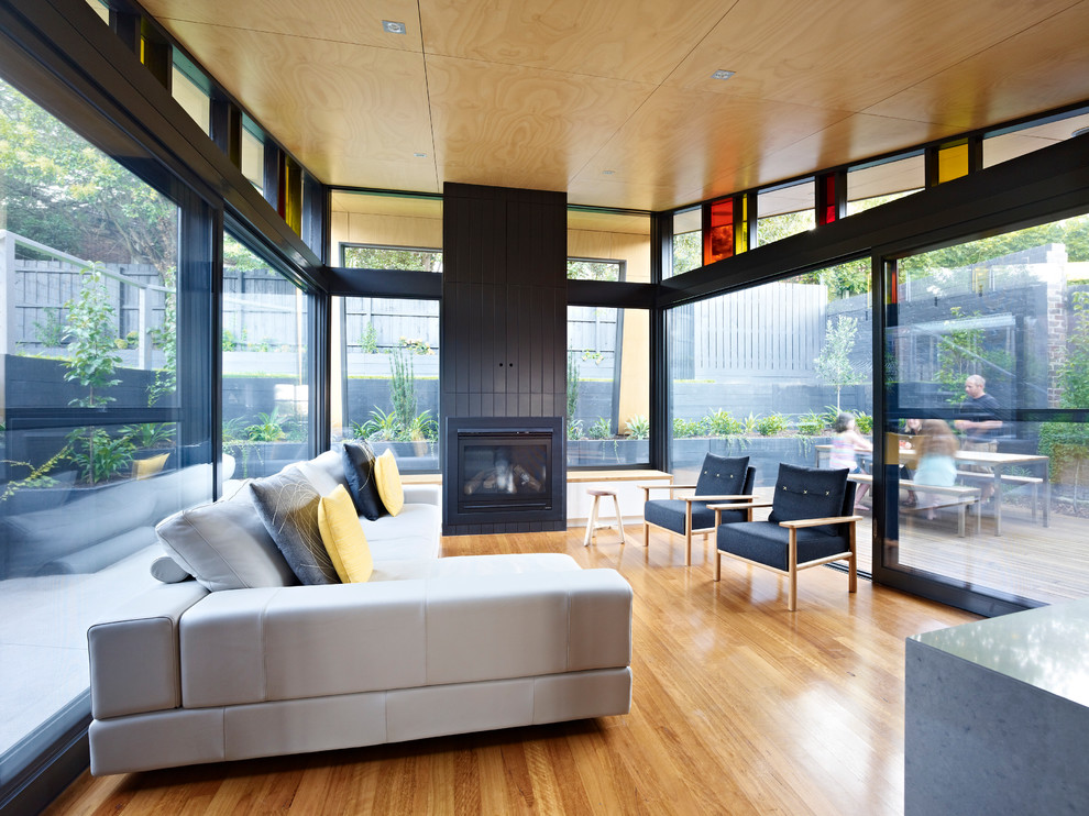 Exemple d'un grand salon tendance ouvert avec un mur noir, un sol en bois brun, une cheminée standard et un téléviseur dissimulé.