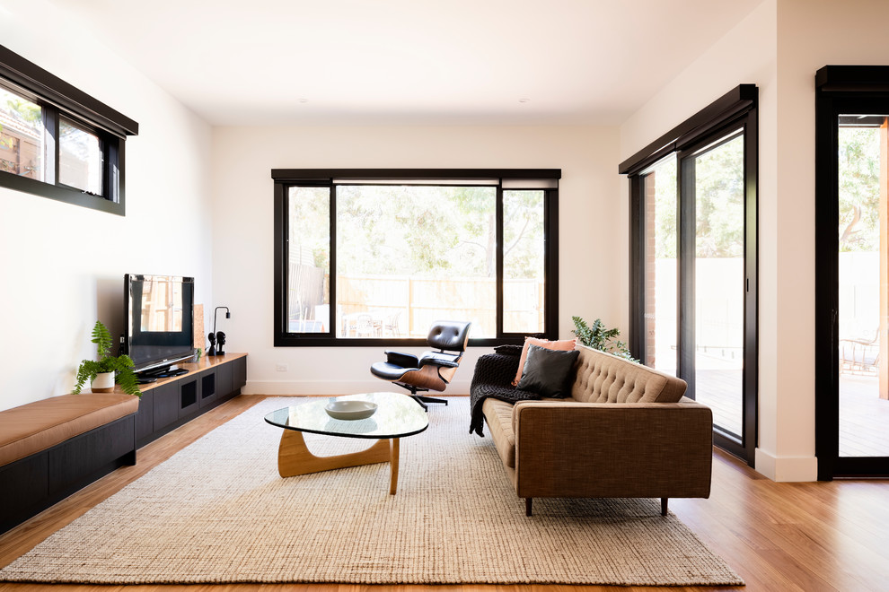 Réalisation d'un salon design ouvert avec un mur blanc, un sol en bois brun, aucune cheminée, un téléviseur indépendant et un sol marron.