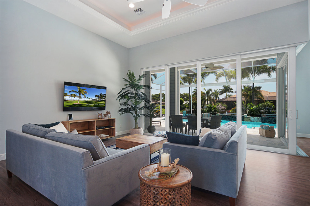Immagine di un soggiorno stile marinaro di medie dimensioni e aperto con pareti blu, pavimento in vinile e TV a parete
