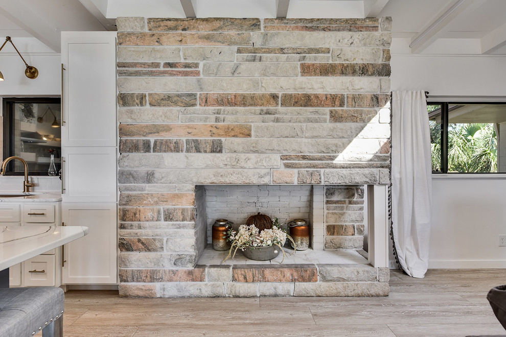 Inspiration pour un salon rustique ouvert avec un mur blanc et un manteau de cheminée en pierre.