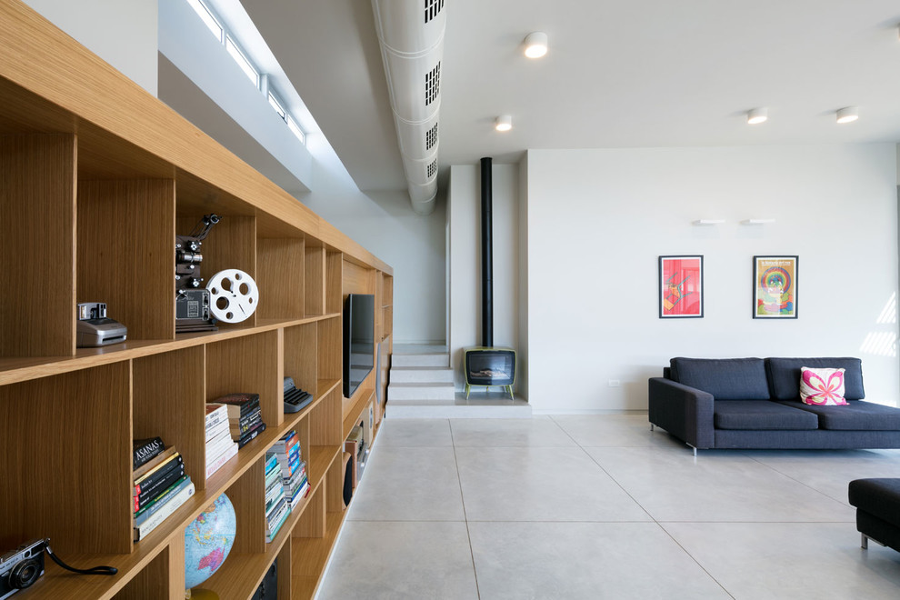 На фото: парадная, открытая гостиная комната среднего размера в стиле лофт с белыми стенами, бетонным полом, печью-буржуйкой, фасадом камина из металла и мультимедийным центром