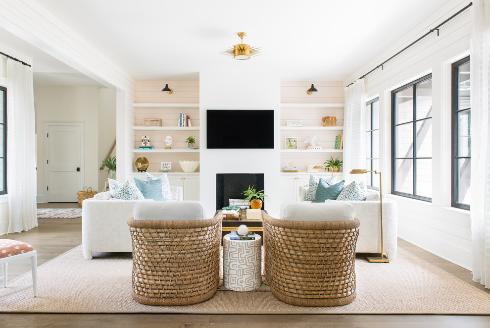 Esempio di un soggiorno costiero con pareti bianche, pavimento in legno massello medio, camino classico, TV a parete e pavimento marrone