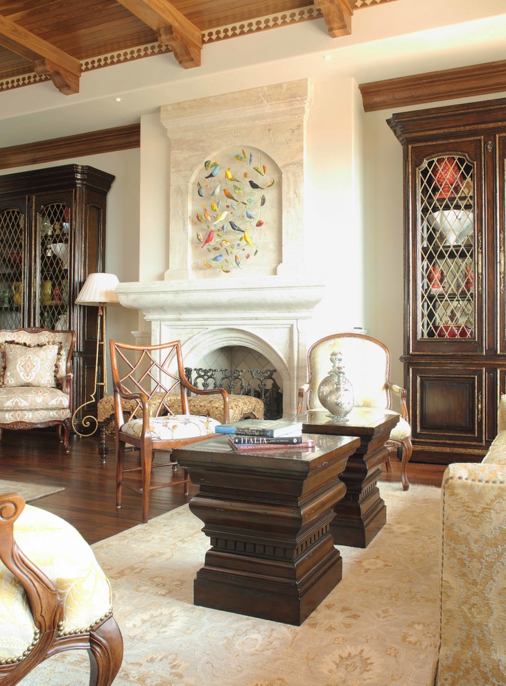 Пример оригинального дизайна: большая открытая гостиная комната в средиземноморском стиле с бежевыми стенами, темным паркетным полом, стандартным камином и фасадом камина из камня