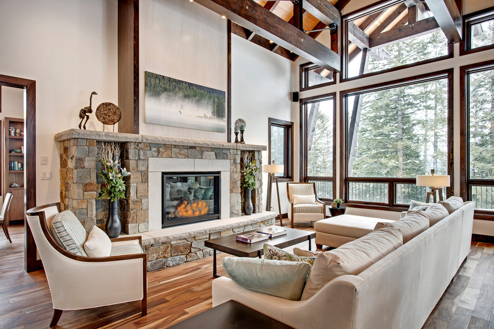 Expansive rustic open plan living room in Vancouver with white walls, medium hardwood flooring, a standard fireplace, a stone fireplace surround and no tv.
