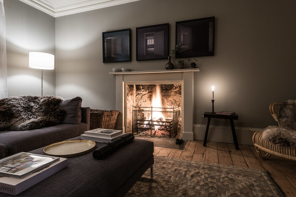 Photo of a medium sized contemporary enclosed living room in Edinburgh with grey walls, medium hardwood flooring, a wood burning stove and a wooden fireplace surround.