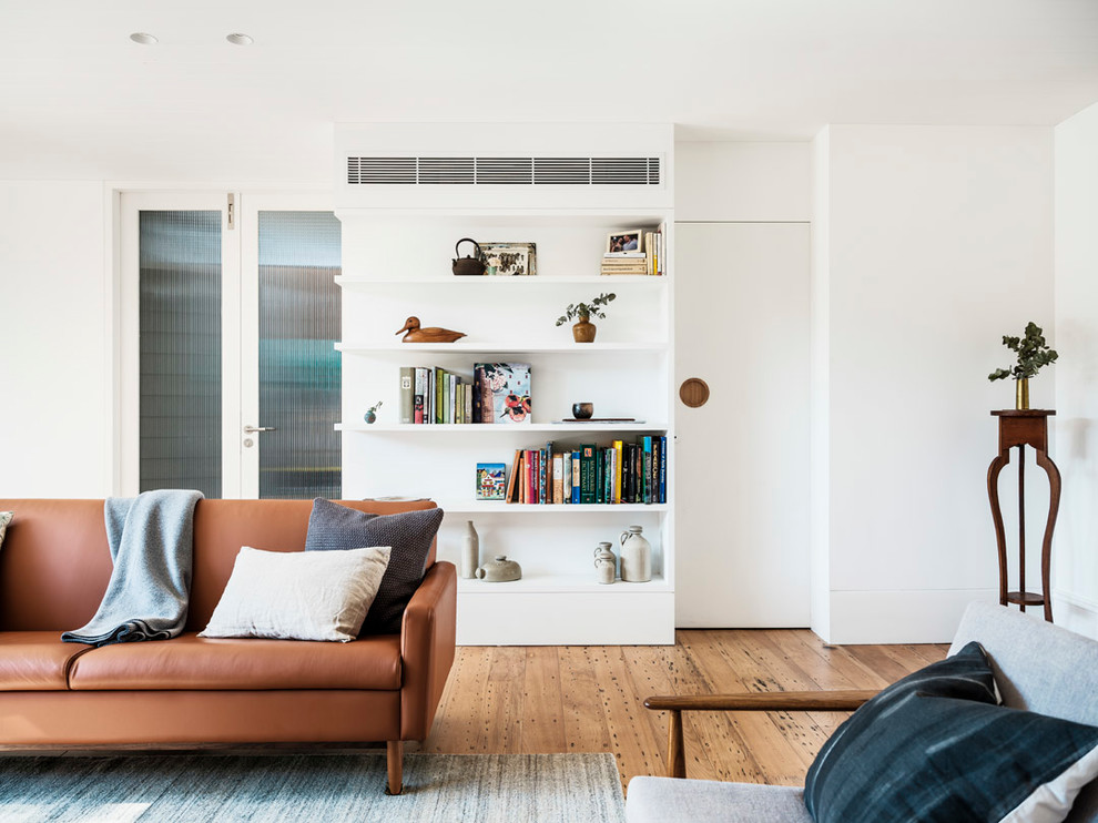 На фото: открытая гостиная комната среднего размера в современном стиле с белыми стенами, светлым паркетным полом, телевизором на стене и бежевым полом без камина