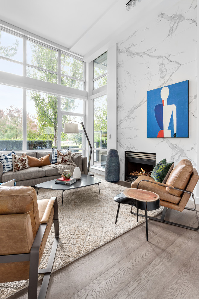 Foto di un grande soggiorno moderno aperto con pareti bianche, parquet chiaro, camino classico, cornice del camino in pietra e pavimento marrone