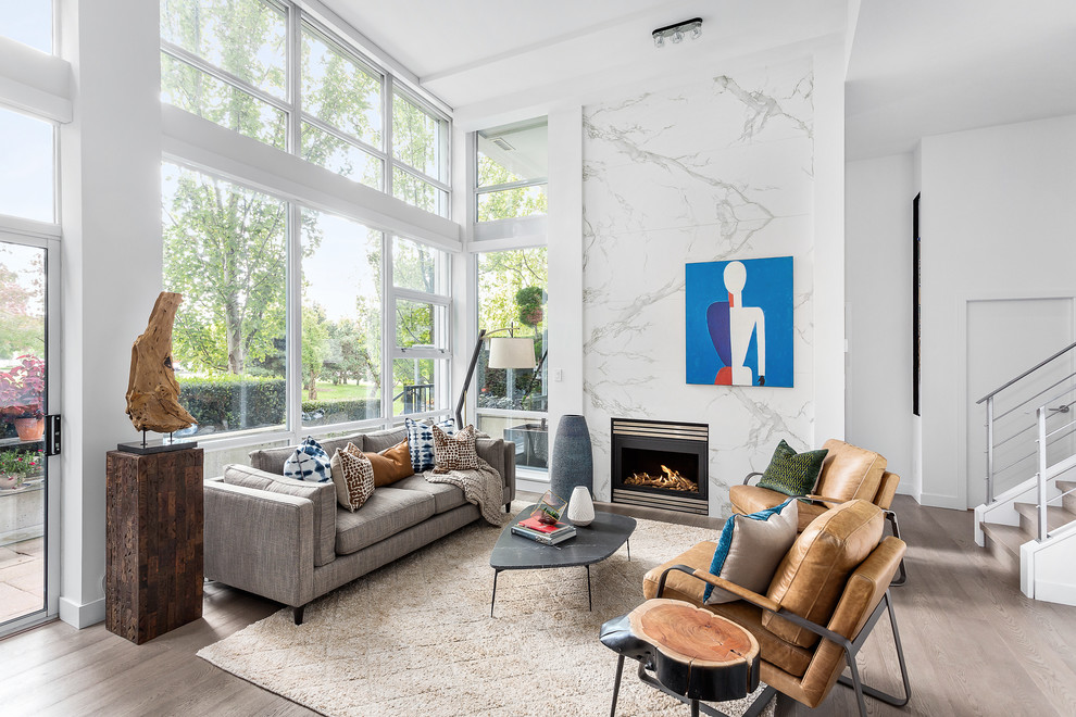 Großes, Offenes Modernes Wohnzimmer mit weißer Wandfarbe, hellem Holzboden, Kamin, Kaminumrandung aus Stein und braunem Boden in Vancouver