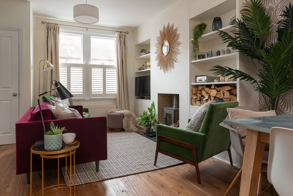 Mittelgroßes, Offenes Stilmix Wohnzimmer mit beiger Wandfarbe, braunem Holzboden, Kaminofen, Kaminumrandung aus Beton und TV-Wand in Hertfordshire