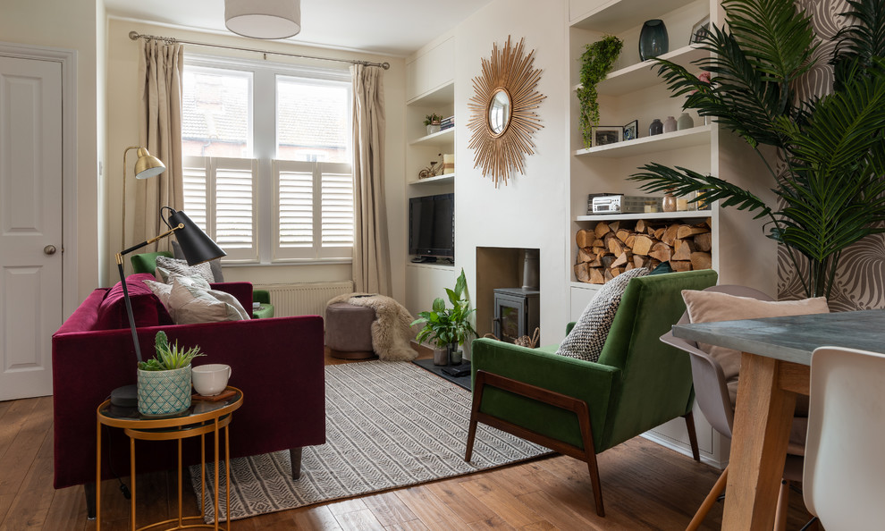 Immagine di un soggiorno boho chic con pareti bianche, pavimento in legno massello medio, stufa a legna, cornice del camino in intonaco e TV autoportante
