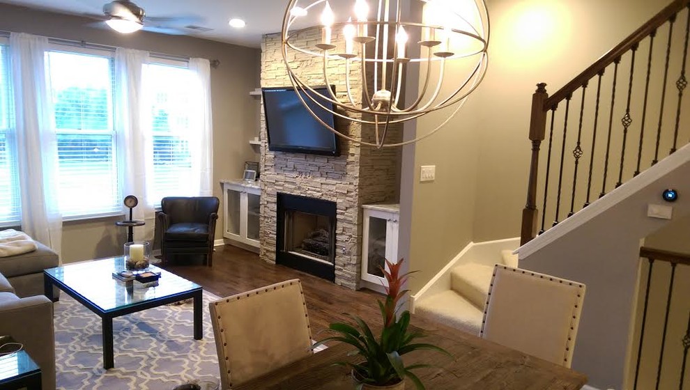 Пример оригинального дизайна: гостиная комната среднего размера в современном стиле с серыми стенами, темным паркетным полом, стандартным камином, фасадом камина из камня, телевизором на стене и коричневым полом