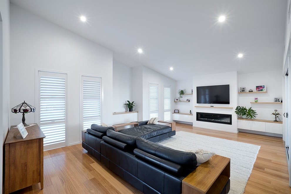 This is an example of a modern living room in Gold Coast - Tweed with white walls and a wall mounted tv.