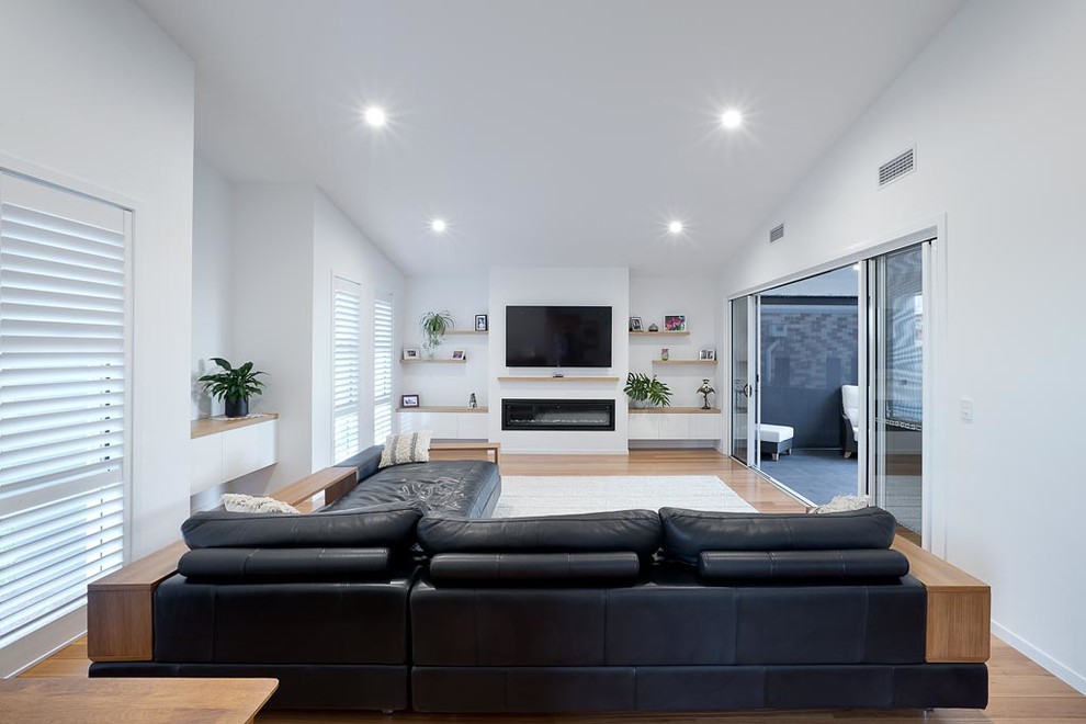 Immagine di un soggiorno moderno con pareti bianche e TV a parete