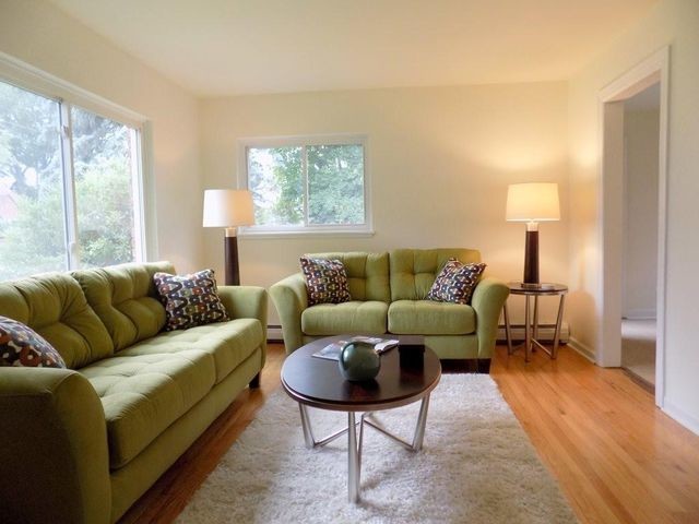Mid-sized trendy enclosed medium tone wood floor living room photo in New York with white walls, no tv and no fireplace