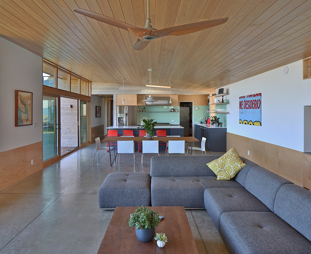 Imagen de salón abierto moderno de tamaño medio con paredes multicolor, suelo de cemento, estufa de leña, marco de chimenea de hormigón y suelo gris