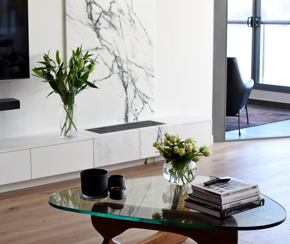 Réalisation d'un salon design de taille moyenne et ouvert avec un mur blanc, parquet foncé, une cheminée ribbon, un manteau de cheminée en pierre, un téléviseur fixé au mur et un sol marron.