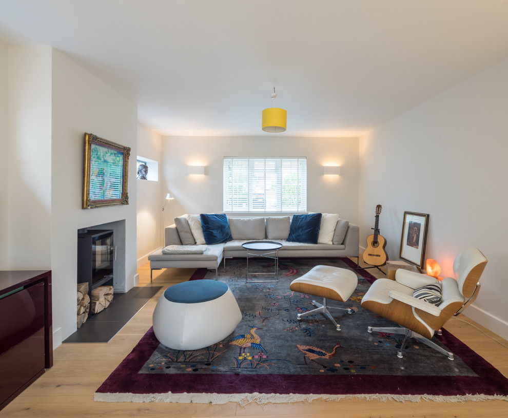 Idee per un soggiorno minimal di medie dimensioni e chiuso con sala formale, pareti bianche, parquet chiaro e stufa a legna